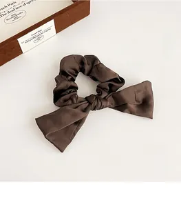 Détail d'un chouchou à nœud en satin moka élégant avec une texture soyeuse vintage