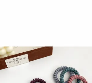 Vue détaillée d'élastiques à cheveux spirales mats en violet, gris et vert foncé
