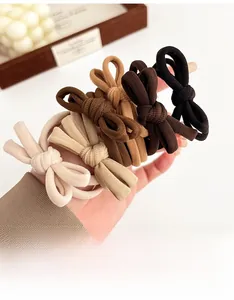 Detail of five earth-toned bow hair ties showing fine ribbed texture and elastic material