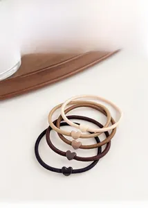 Detailed view of 5-piece heart-shaped elastic hair ties in gradient earth tones on a wooden tray