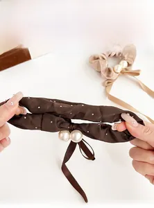 Detail of satin bow scrunchie with large pearls and sparkling rhinestones