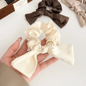 Chouchou élégant en satin avec nœud en tons terre pour coiffures queue de cheval chic