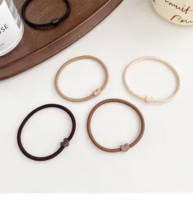Detail of high-elasticity hair ties with matte heart accents in neutral earthy tones