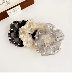 Gros plan de chouchous en organza noir, beige et gris avec perles et paillettes