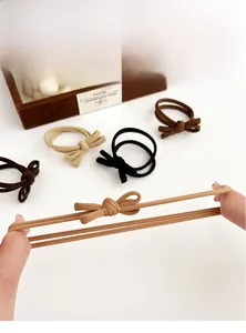 Elastic bow hair ties in coffee tones shown being stretched to demonstrate high durability