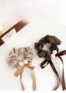 Detail of satin scrunchies with rhinestones, elegant pearls, and ribbon bow accents