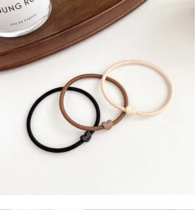 Close-up of three elastic hair ties with matte heart charms in black brown and beige