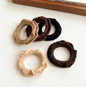 Detail of ruffled elastic hair ties in neutral tones on a clean white surface