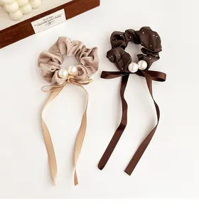 Detail of satin scrunchies set with rhinestones, pearls and ribbons on white background