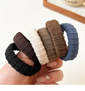 Close-up of thick ribbed cotton hair ties in black, brown, and cream colors