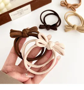 Detailed close-up of earth-toned bow hair ties featuring ribbed fabric and elastic loops