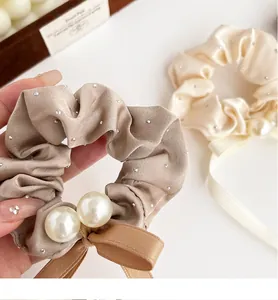 Detail of elegant satin scrunchies with sparkling rhinestones, pearls, and ribbon bows