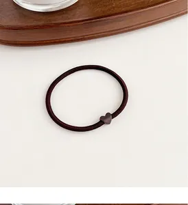 Close-up of durable elastic coffee brown hair tie with a matte heart-shaped charm