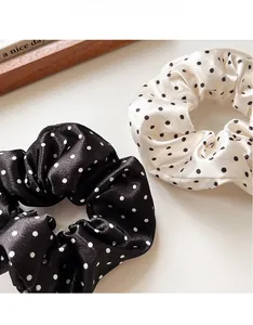 Detail of black and beige polka dot satin scrunchies set with a silky texture finish