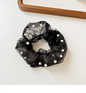 Détail d'un chouchou en organza noir avec perles blanches élégantes et texture de maille fine