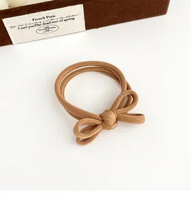 Detail of light brown bow hair tie with ribbed fabric texture on seamless elastic band
