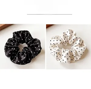 Detailed view of polka dot satin scrunchies in black and white with soft silky texture