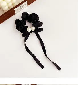 Close-up of black polka dot hair scrunchie with long ribbon and white pearl accents