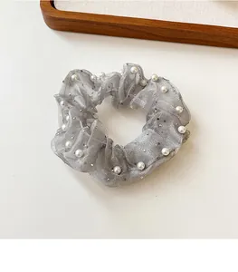 Vue détaillée du chouchou en organza gris avec des perles blanches et des paillettes argentées