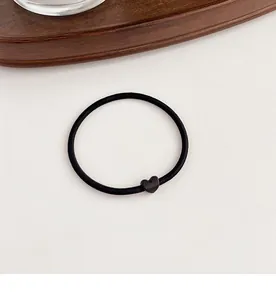 Detailed view of the elastic black hair tie with a minimalist matte heart accessory