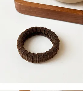 Detailed texture of thick coffee brown ribbed elastic hair tie on a minimalist background