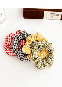 Close-up of four plaid fabric hair scrunchies in red, black, yellow and green colors