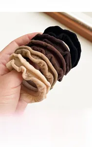 Close-up of ruffled seamless hair ties in assorted earth tones held by hand