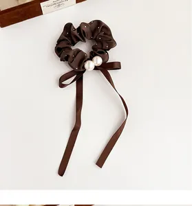 Detail of brown polka dot silk scrunchie with large pearls and long bow ribbon