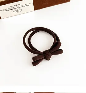 Close-up of a coffee brown high-elastic hair tie with a soft bow on a minimalist background