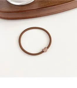 Close-up of a coffee-colored elastic hair tie featuring a matte heart-shaped buckle