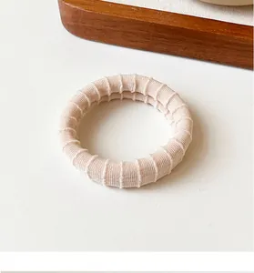 Close-up of cream-colored elastic hair tie with textured vertical ribbed pattern