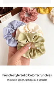 Nahaufnahme von verschiedenen Seiden-Scrunchies in Pastellfarben auf Holztablett