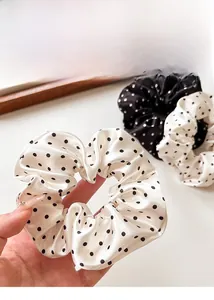 Detailed view of polka dot satin scrunchies in classic black and white color patterns