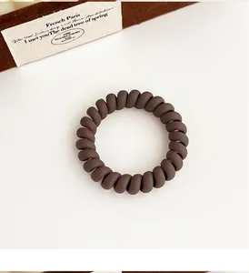Gros plan d'un élastique spirale marron mat à haute élasticité sur une surface blanche