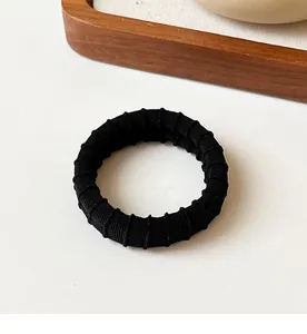 Close-up of black high-elastic hair tie with durable ribbed texture for daily hairstyling