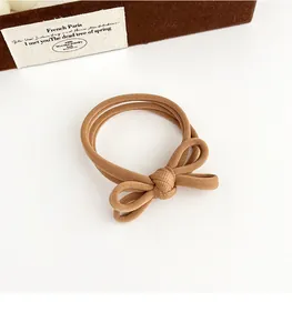 Detail of khaki bow hair tie with high-elastic ribbed texture for seamless ponytail styling