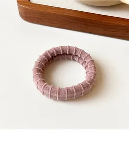 Detail view of pink elastic hair band with ribbed texture on a white background