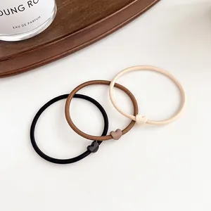 Set of high elastic hair ties in beige and brown with matte heart charms on wood tray
