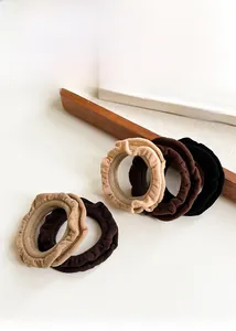 Close-up of three ruffled elastic hair ties in beige, coffee and black fabric