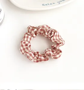 Detalle de coletero de tela de cuadros vichy rojos con textura plisada suave en fondo blanco