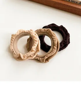 Detailed view of three coffee-colored ruffled hair scrunchies on a white surface