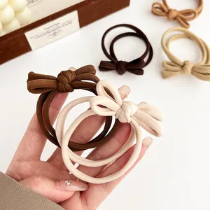 Coffee and beige bow hair ties with ribbed texture shown in a minimalist aesthetic setting