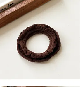 Close-up of soft coffee-brown ruffled scrunchie with plush texture on cream background