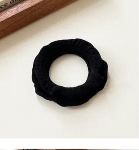 Macro shot of durable black ruffled elastic hair scrunchie with fine pleated fabric texture