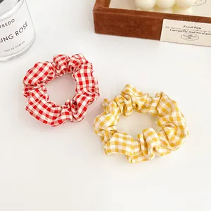 Coleteros de cuadros vichy rojos y amarillos sobre un escritorio blanco minimalista