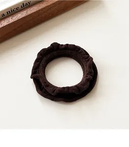 Detail of high-elastic coffee brown ruffled scrunchie with soft velvet texture