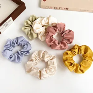 6er-Set bunte Satin-Haargummis in Pastelltönen auf einem minimalistischen Hintergrund