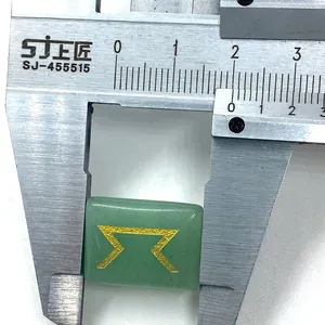 Macro shot of green aventurine stone measuring 18mm width with golden engraved rune symbol