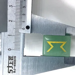 Macro detail of a green gemstone rune stone with golden engraving being measured by a caliper