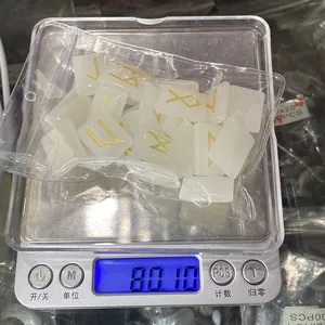 Close-up of translucent rune stones with gold engraving being weighed on a scale